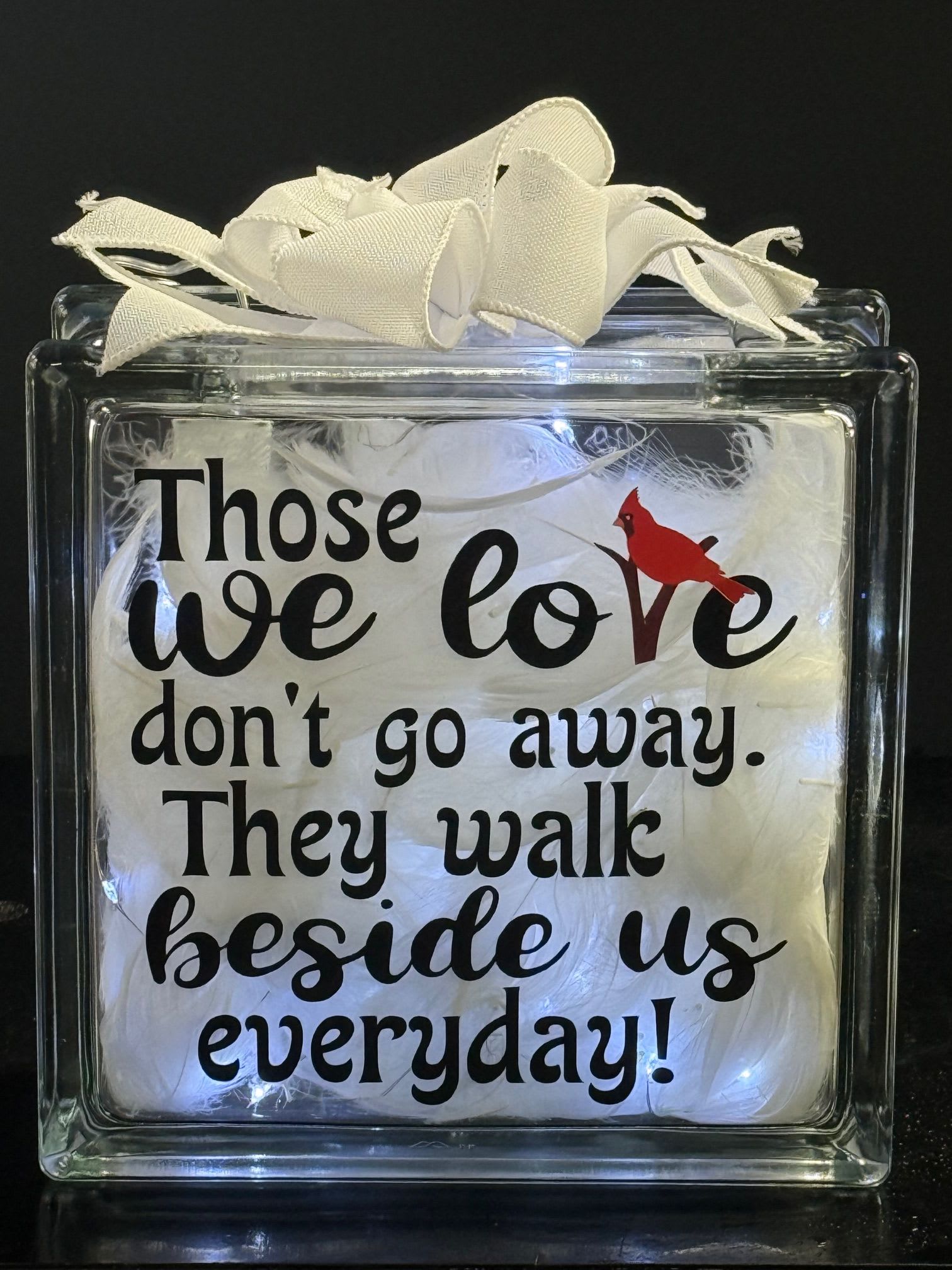 Decorative glass block with a white ribbon and printed quote