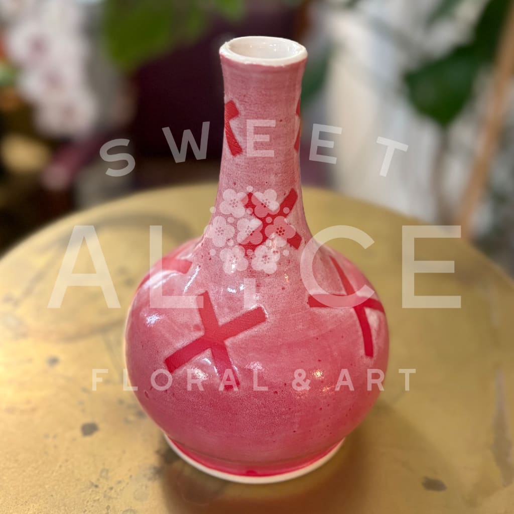 Pink ceramic vase with white floral accents and a narrow neck