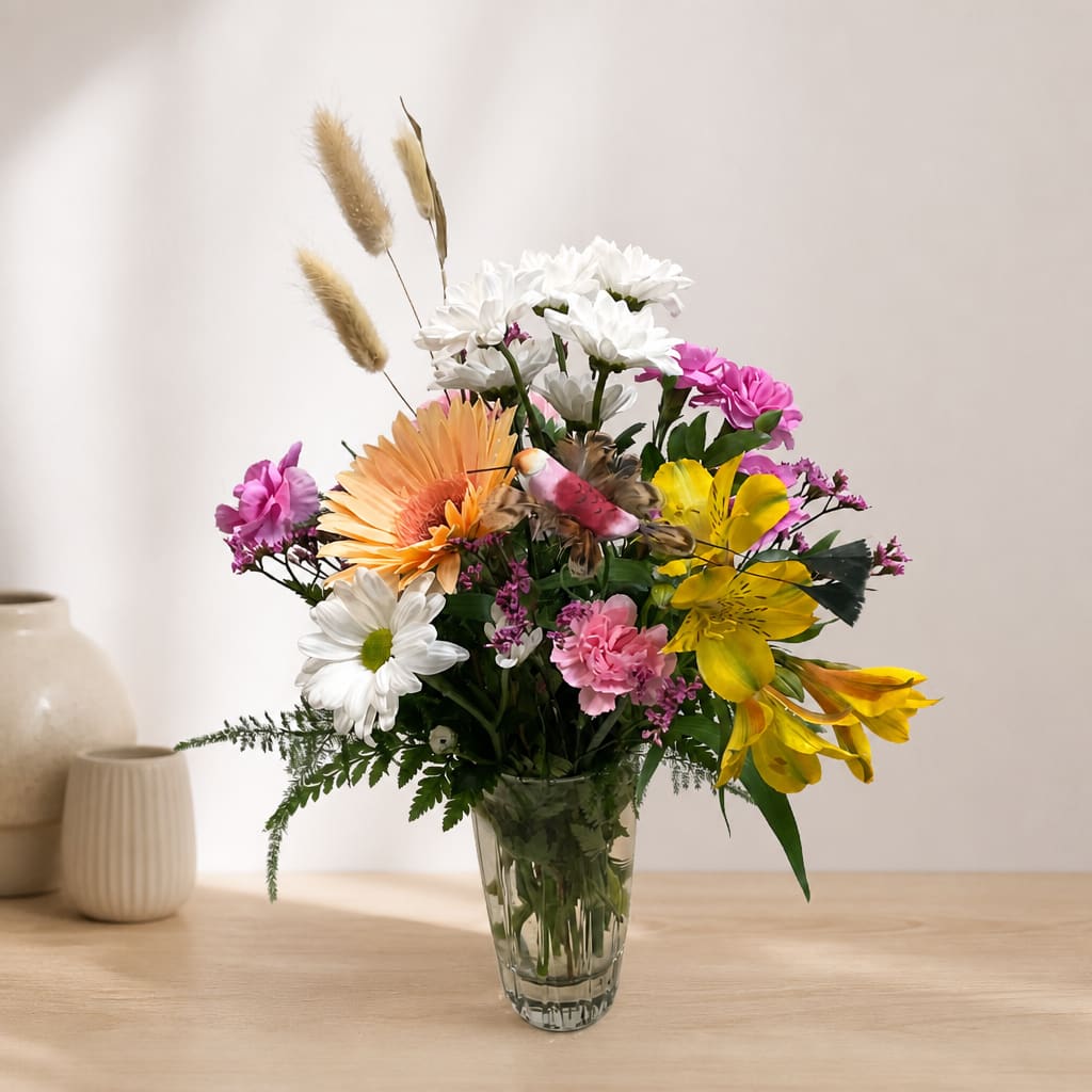 Mixed bouquet of daisies, lilies, and pink flowers in a clear glass vase