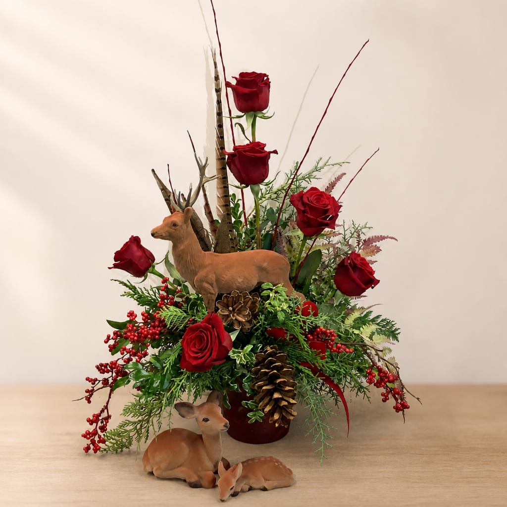 Red roses arranged with pinecones and deer figurines in a vase