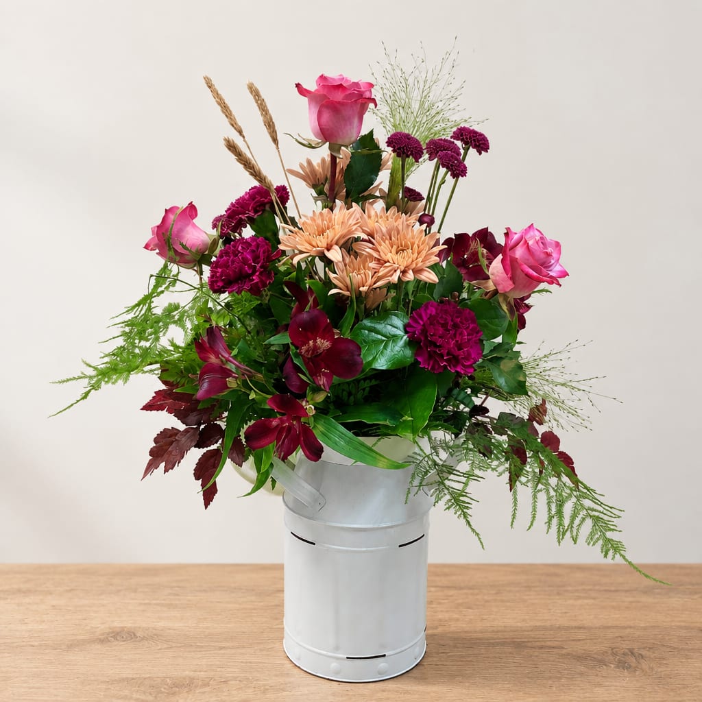 Mixed bouquet in a white metal bucket with pink and burgundy flowers