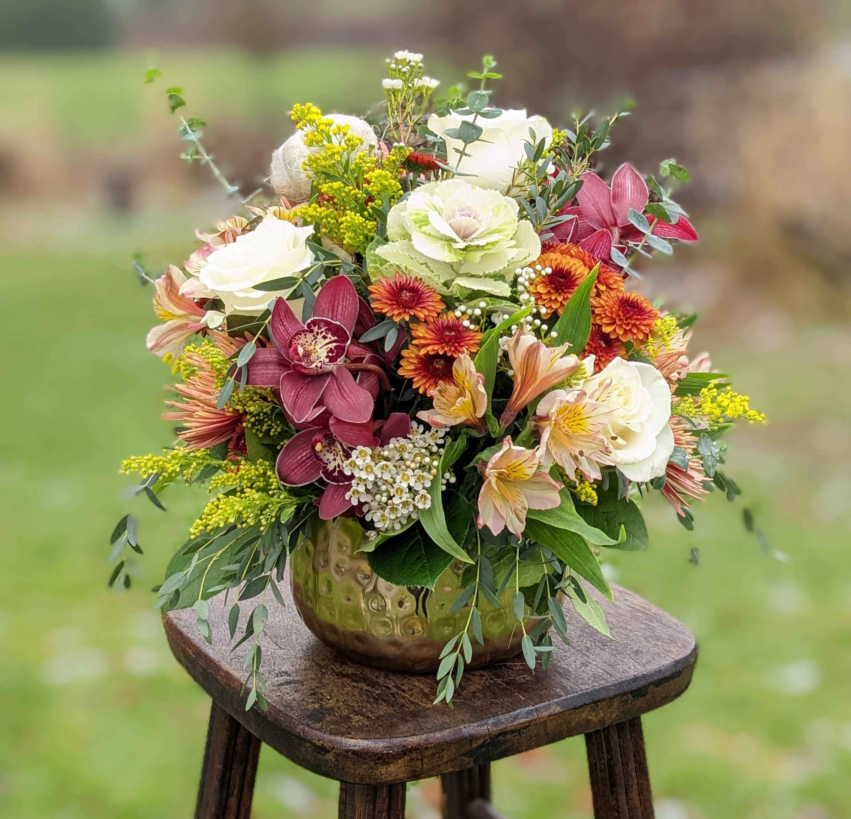 Mixed floral arrangement in a gold vase with white, pink, and orange blooms