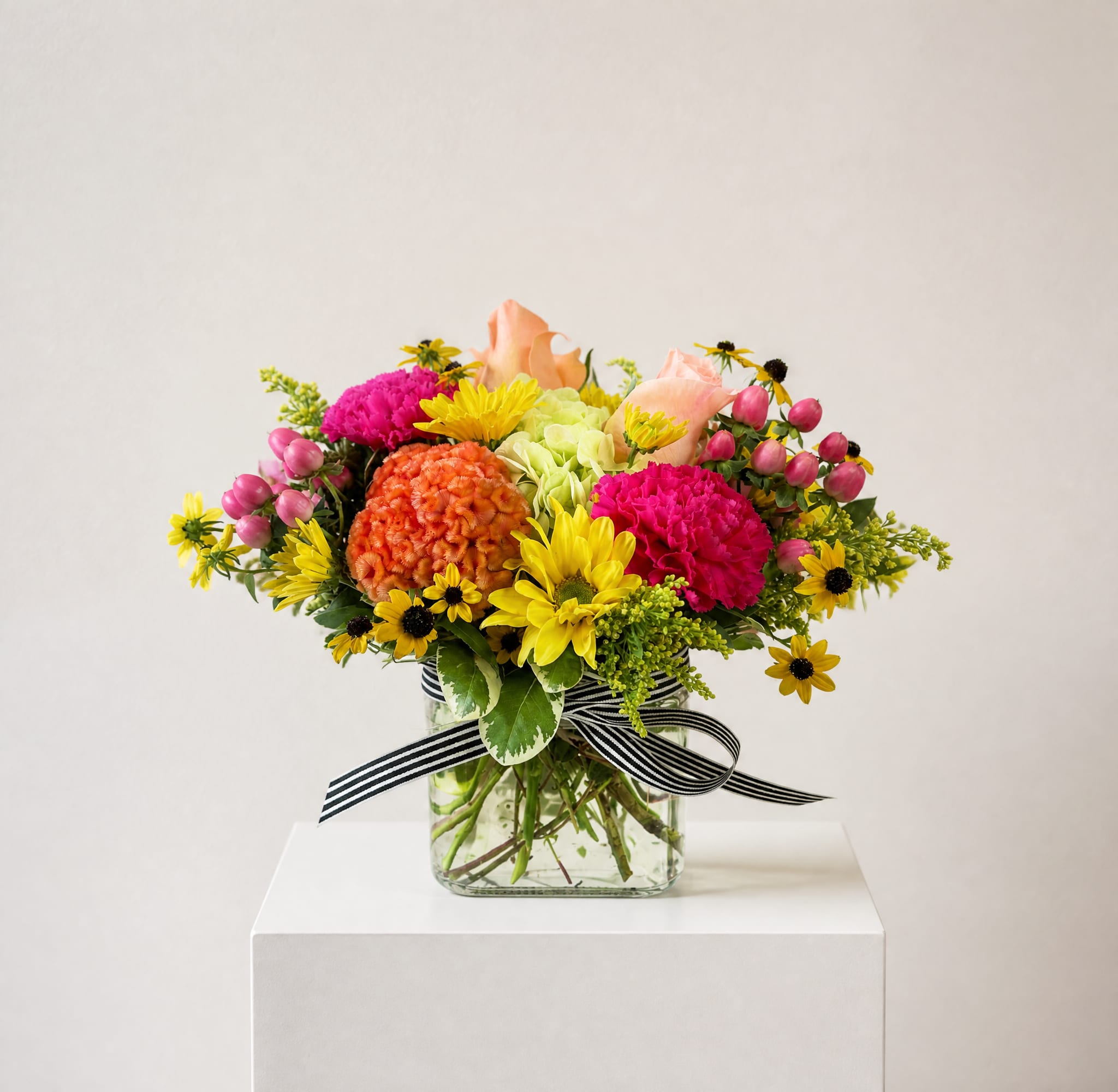 Mixed bouquet in a glass vase with pink, yellow, orange, and peach flowers