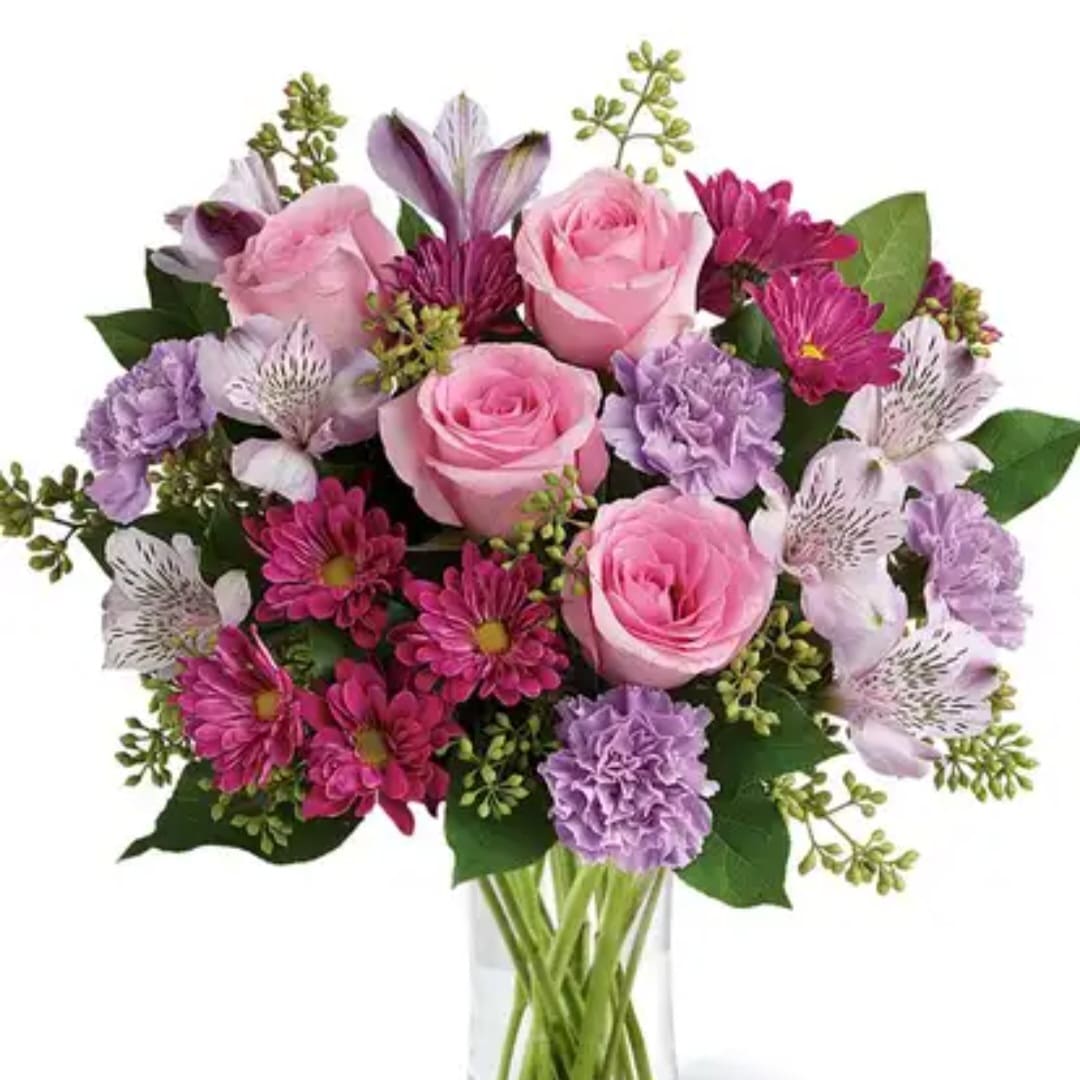 Pink roses and purple mixed flowers in a clear glass vase