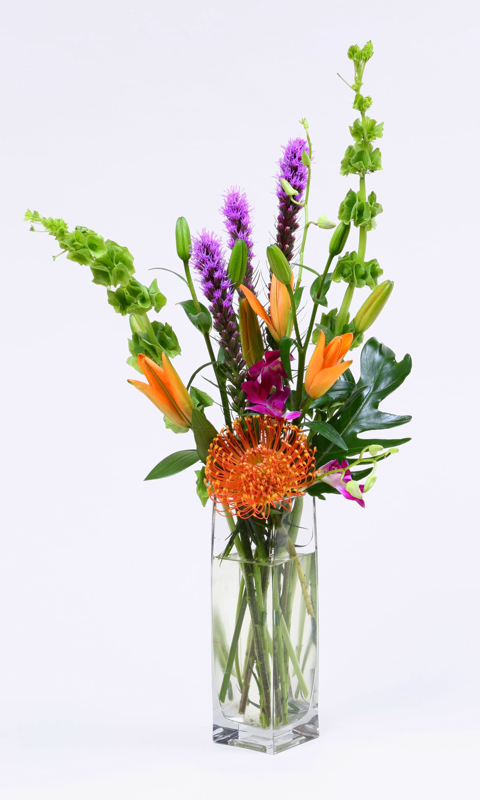 Tall mixed bouquet in a clear glass vase with orange and purple blooms