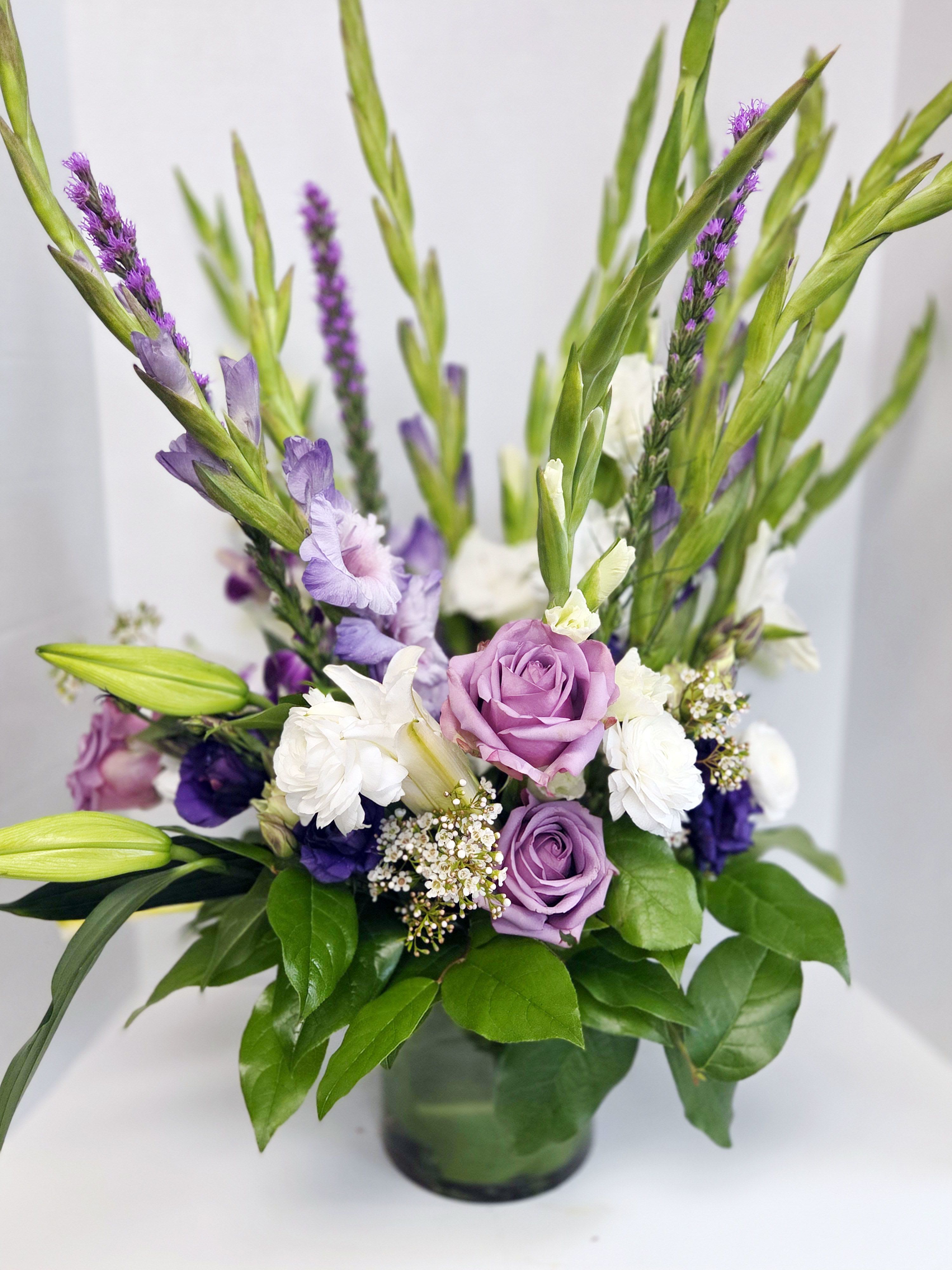 Purple and white flowers arranged in a glass vase