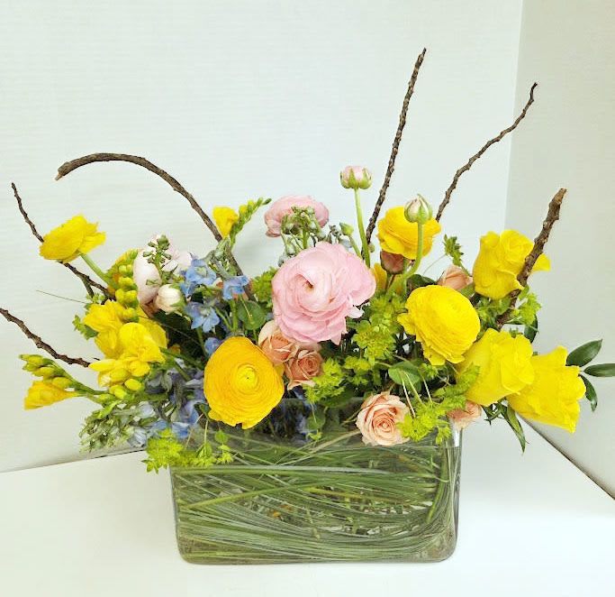 Yellow and pink mixed flower arrangement in a glass vase