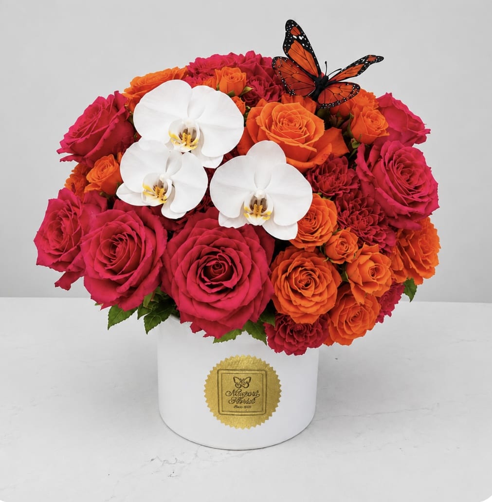 Pink and orange roses with white orchids in a white hat box
