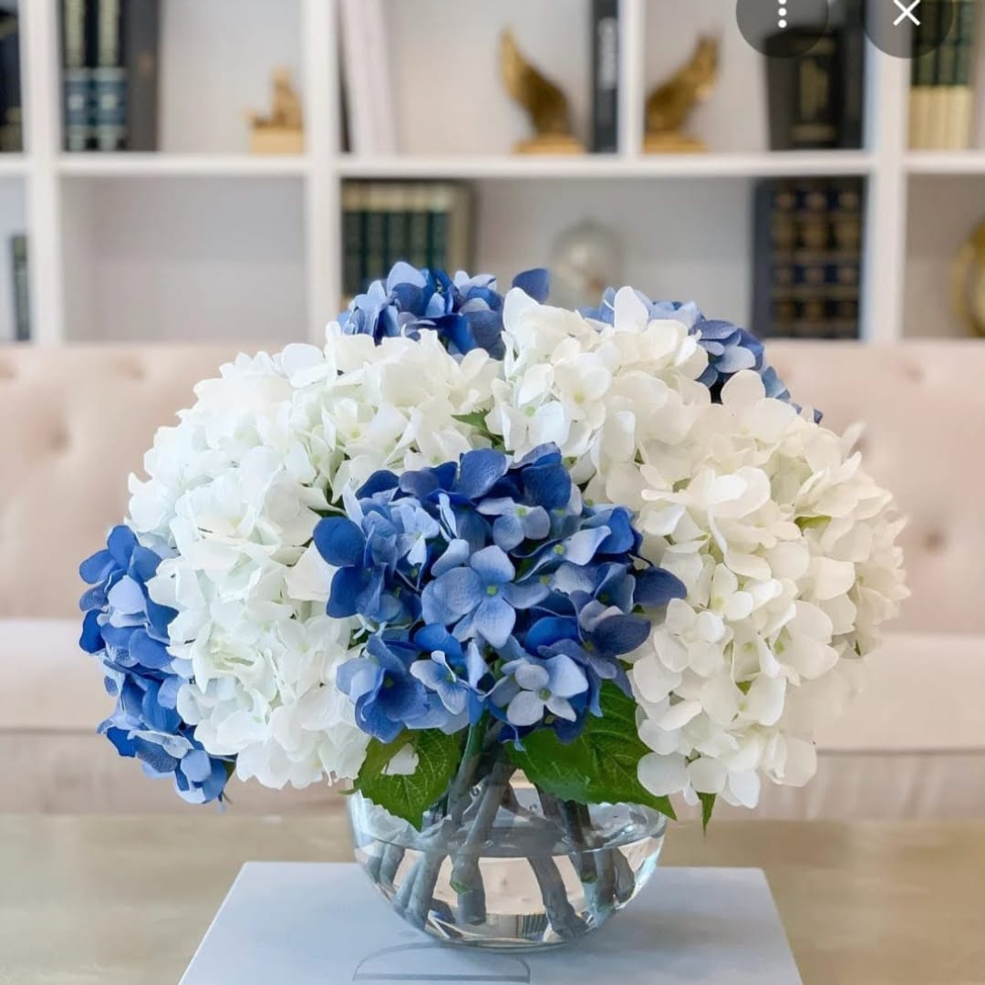 Blue and white hydrangeas arranged in a clear glass bowl vase