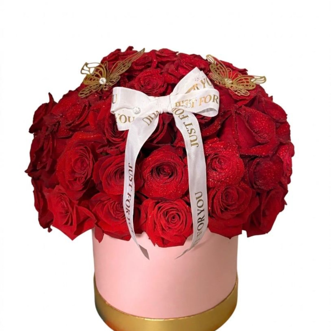 Red rose arrangement in a pink round box with a white ribbon
