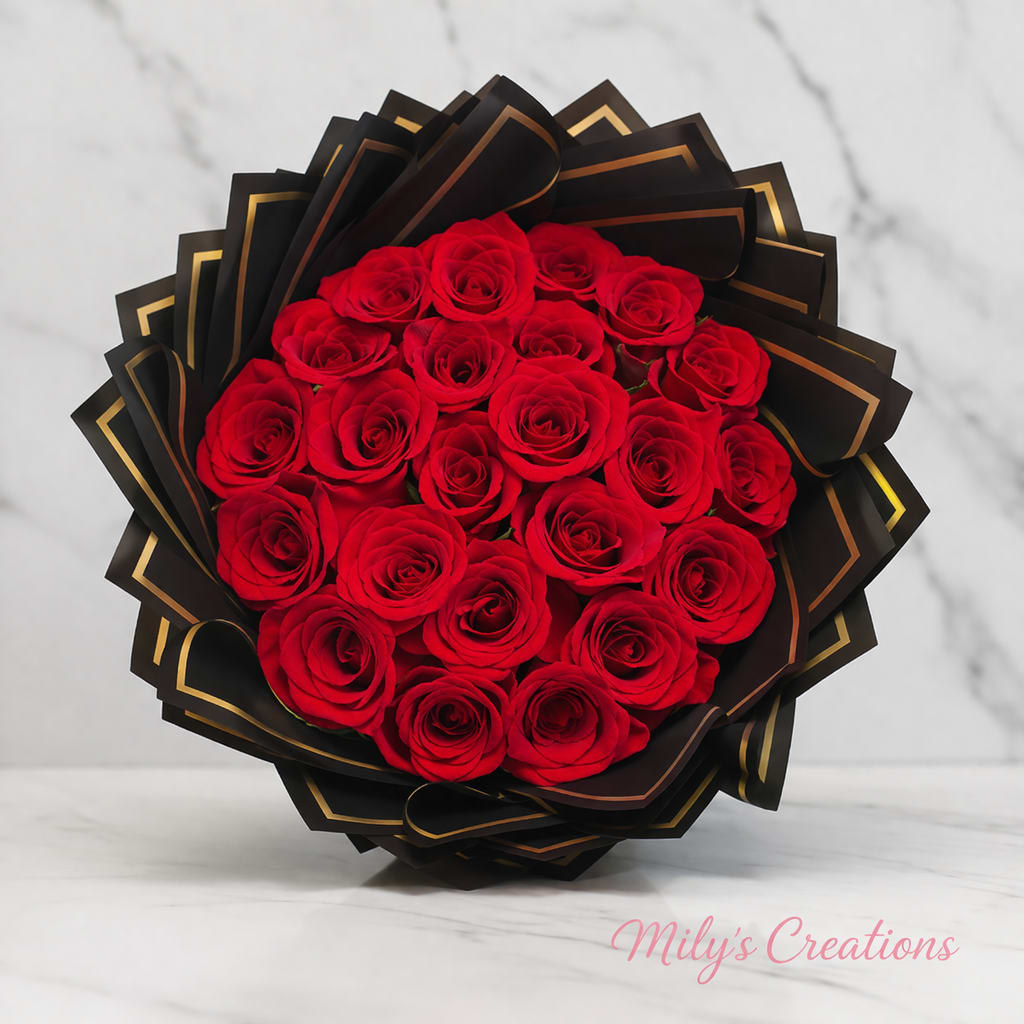 Round bouquet of red roses wrapped in black and gold paper on a marble surface