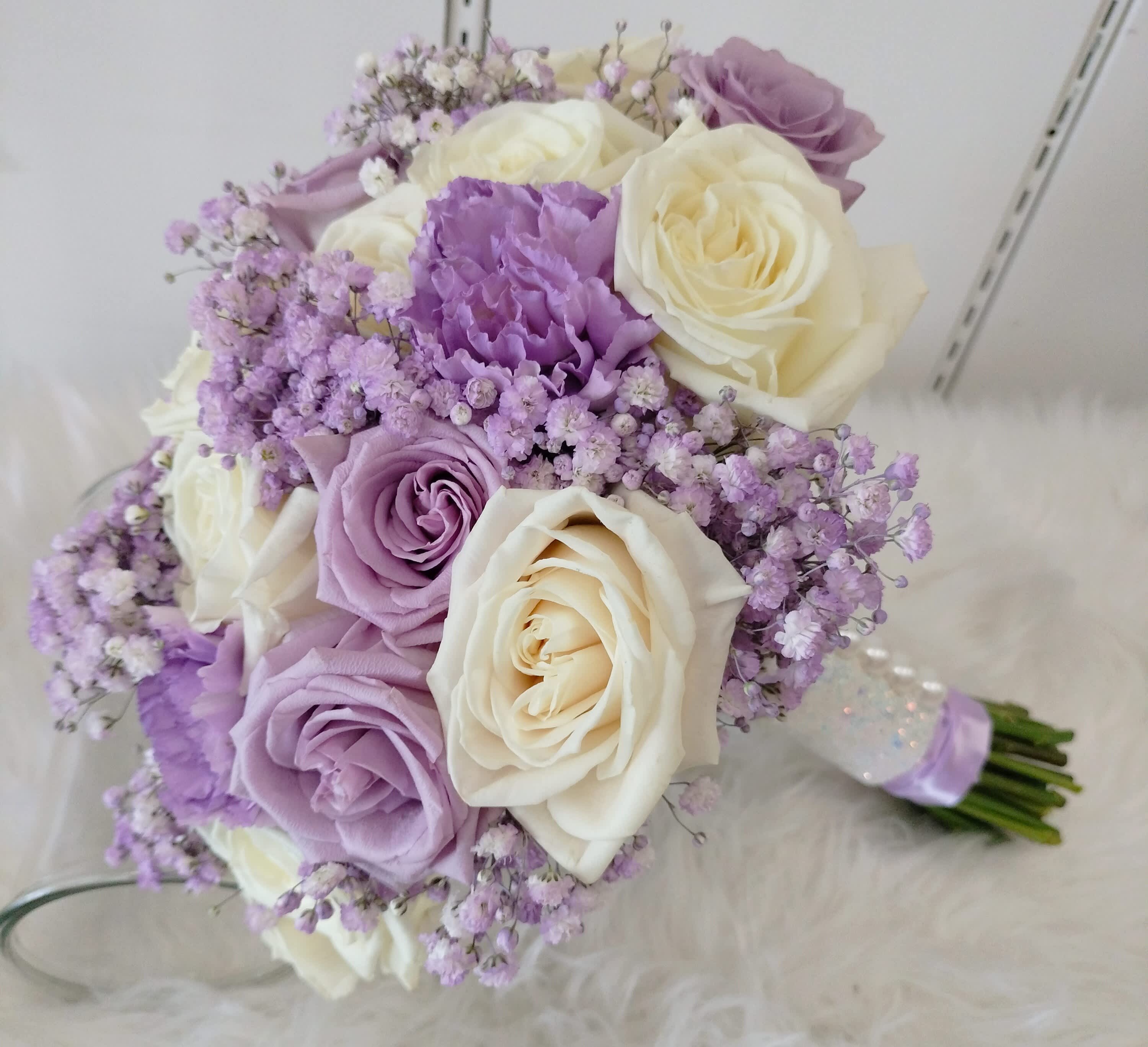 Bouquet of cream and lavender roses with small purple filler flowers