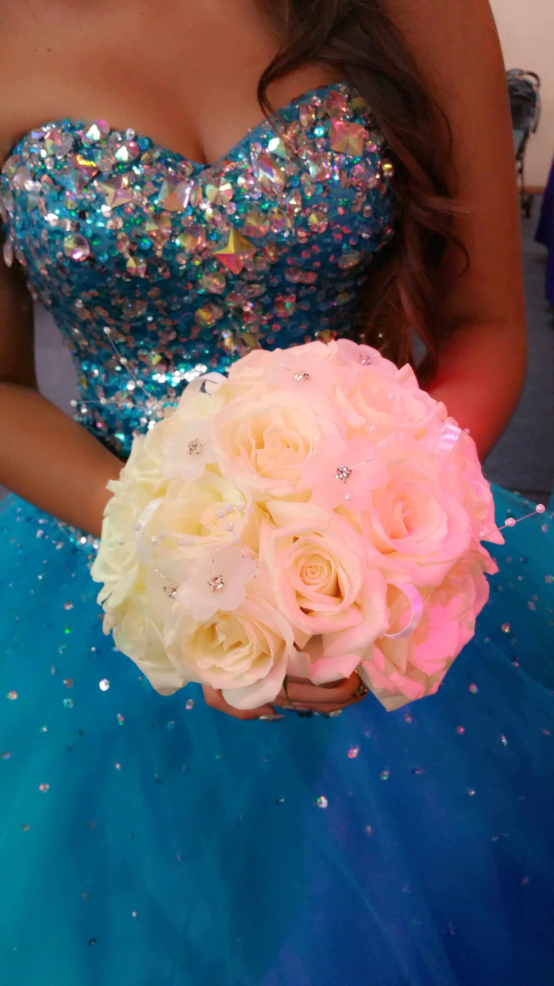 Woman in a blue sequined dress holding a pale pink and white rose bouquet