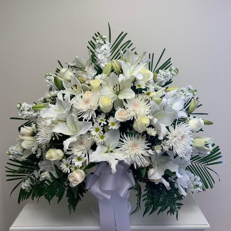 Large white floral spray with lilies and daisies, tied with a lavender ribbon