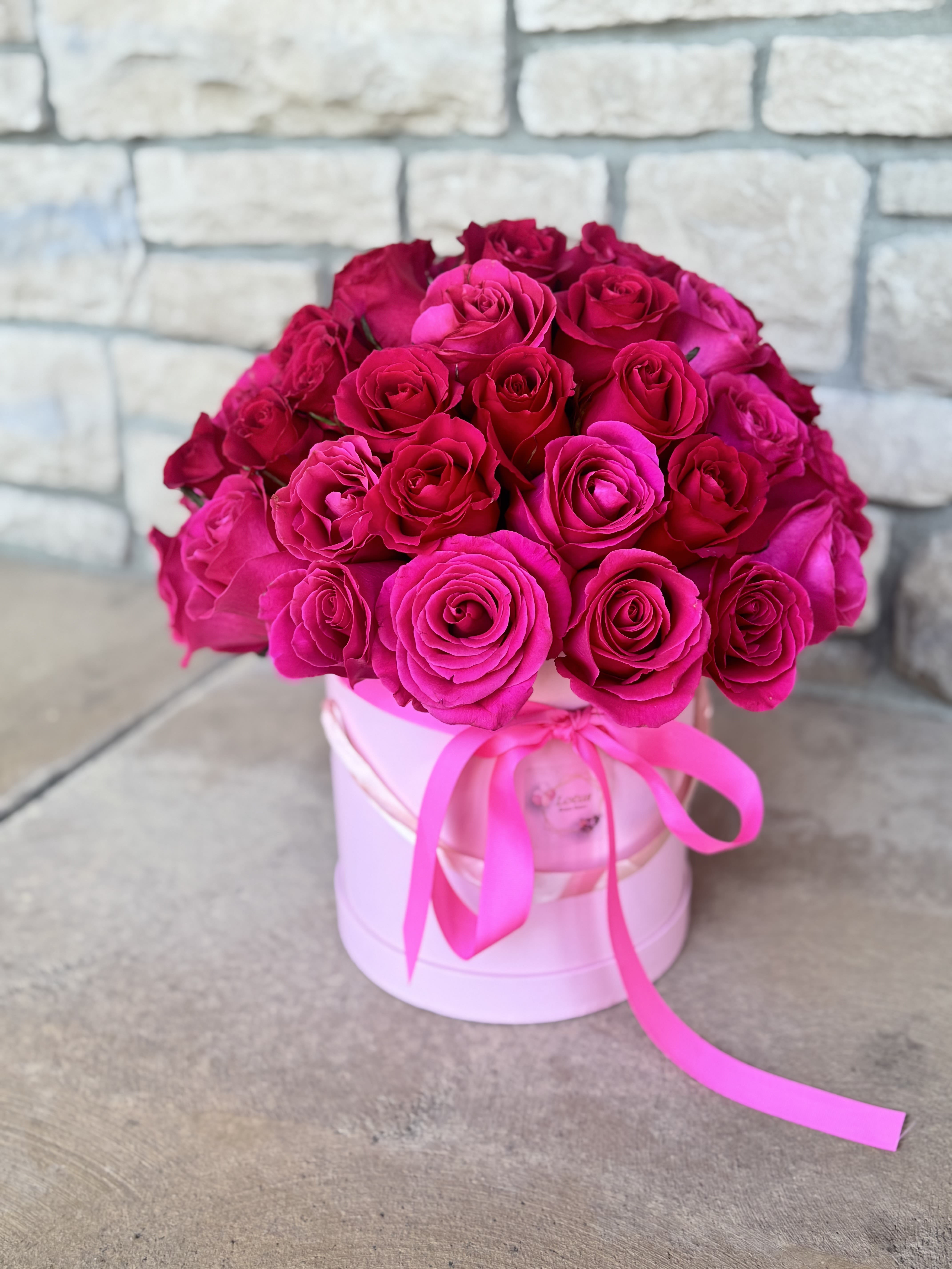 Bouquet of hot pink roses in a pink hat box with ribbon