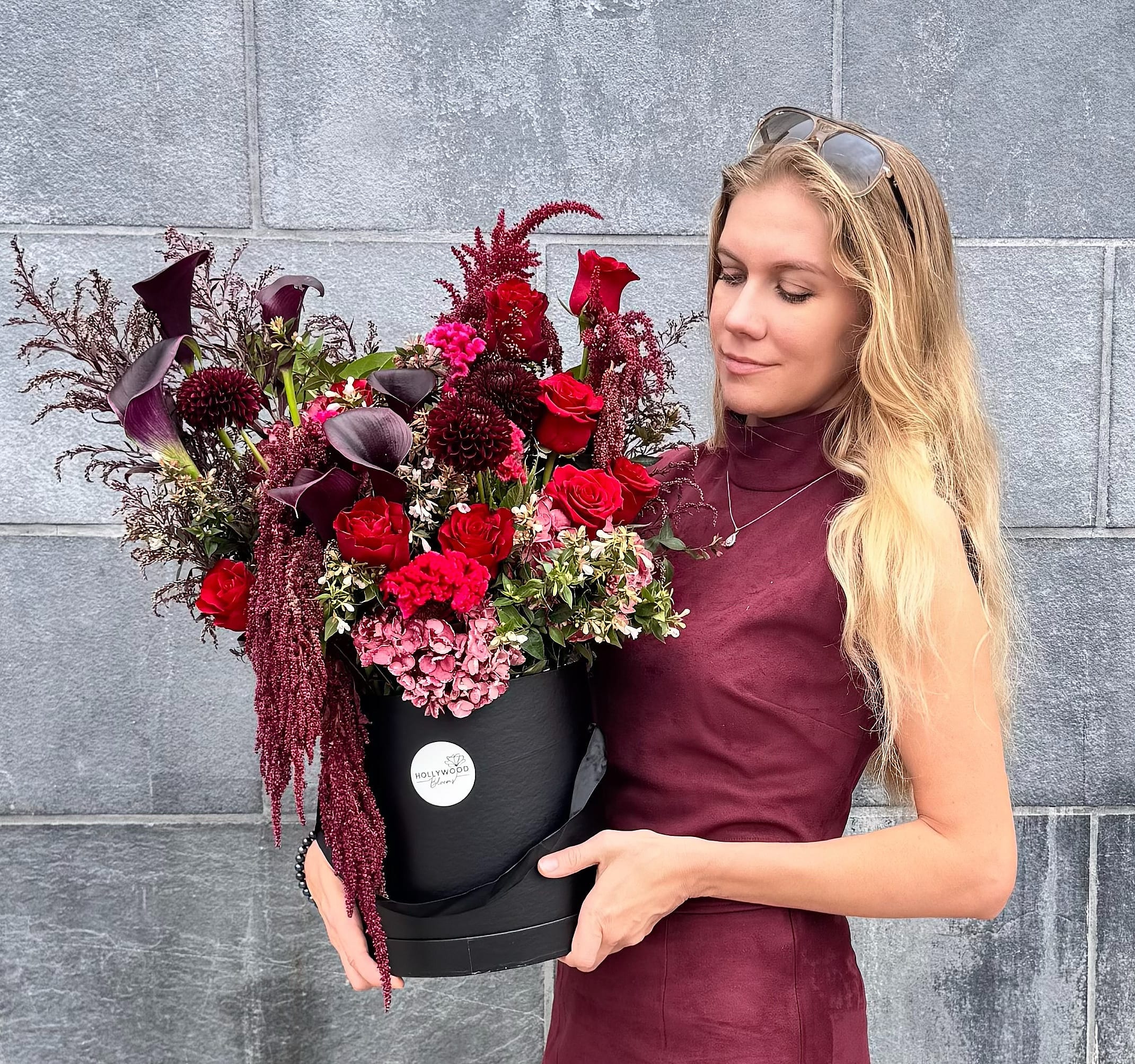 Woman holding a black box of red and burgundy flowers