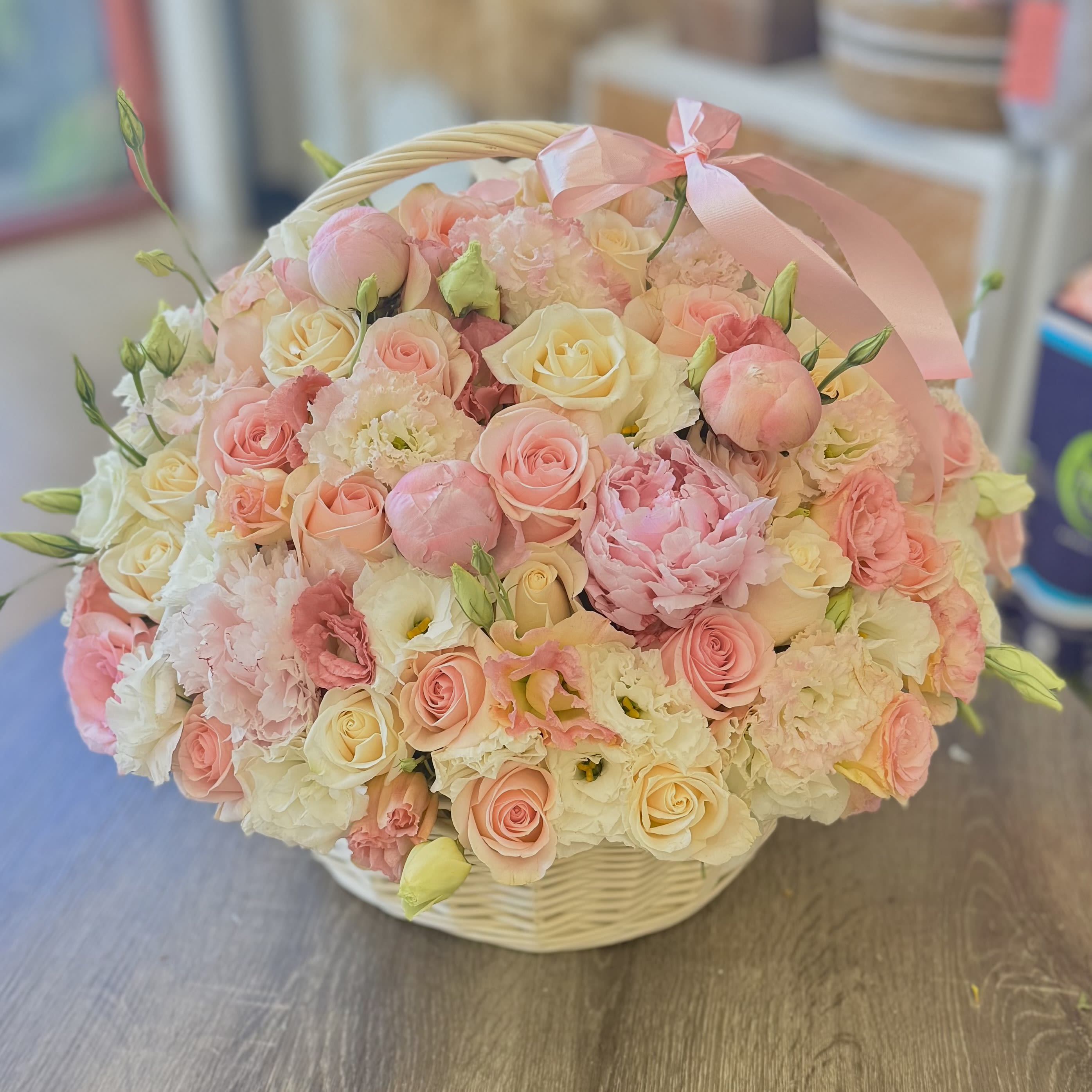 Basket of pink and cream roses with peonies and ribbon