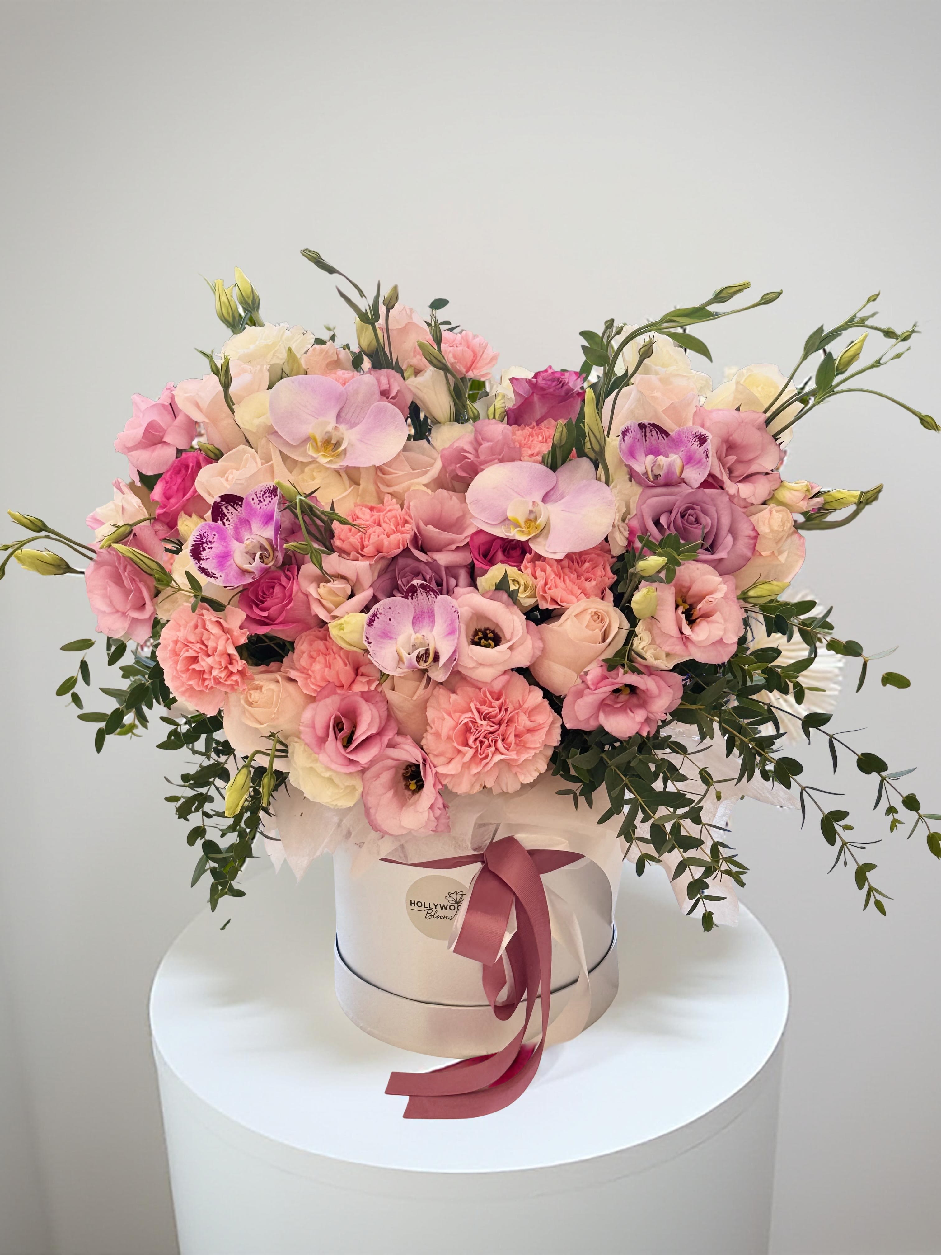 Pink and cream flower arrangement in a round hat box with ribbon