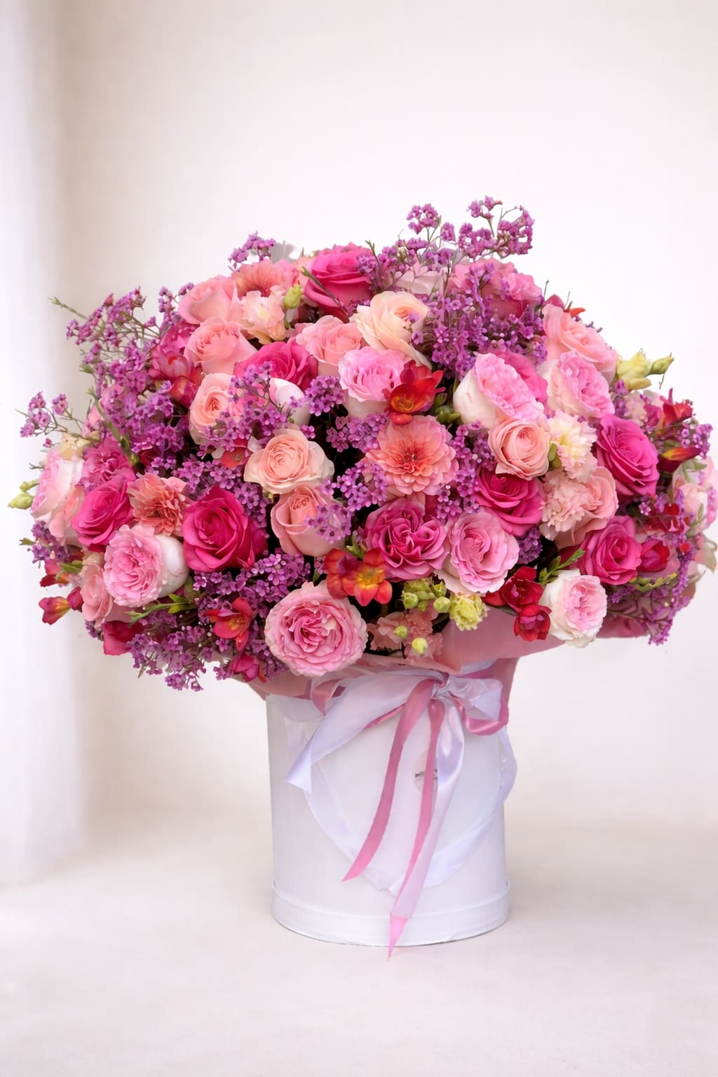 Large pink and purple rose bouquet in a white hat box with ribbon