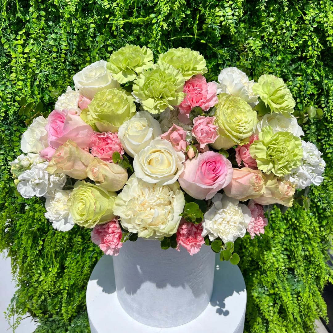 Round bouquet of pink, white, and green flowers in a white vase