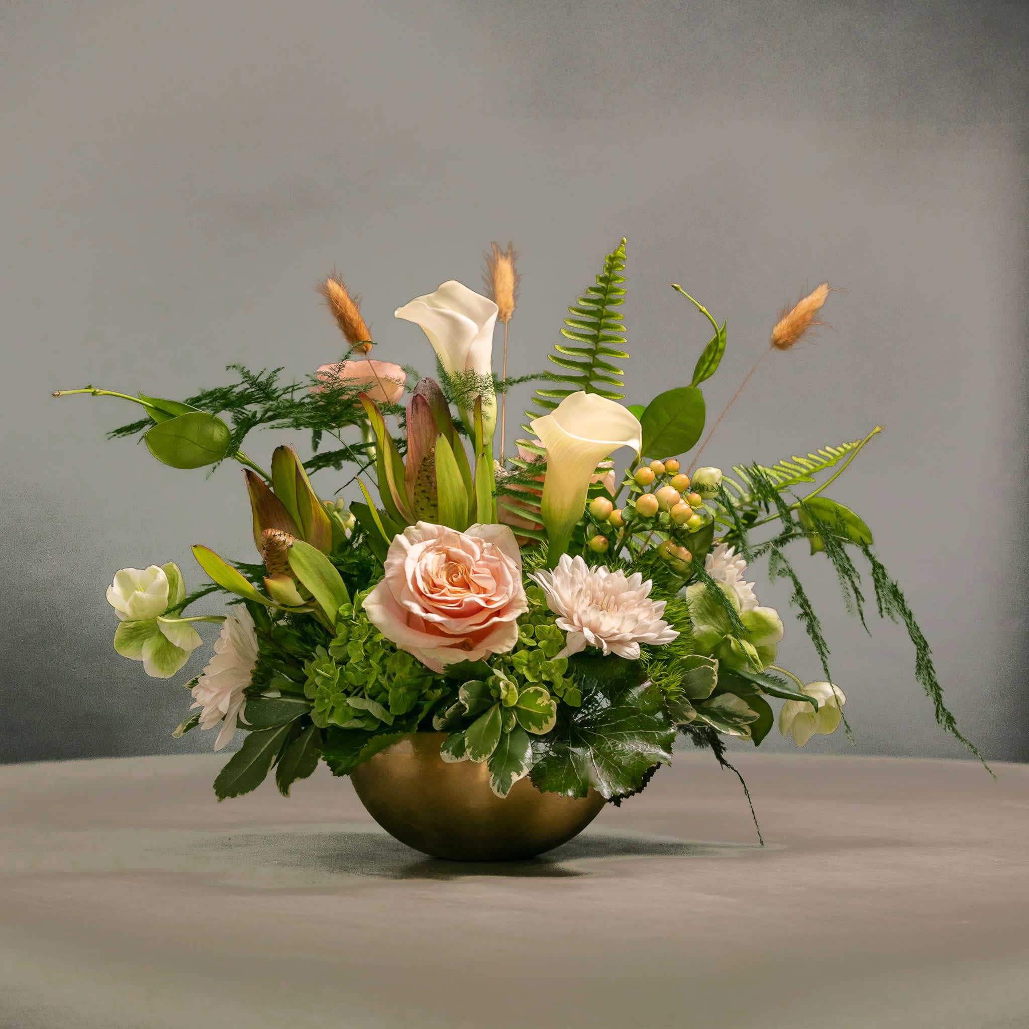 Mixed floral arrangement in a gold bowl with pale pink and white blooms