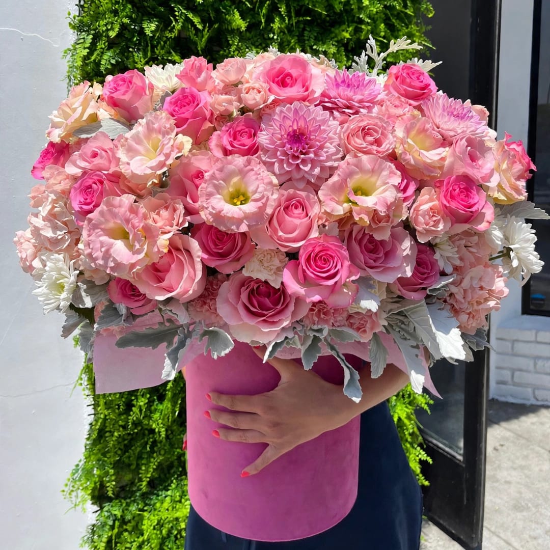 Large pink bouquet of roses and mixed blooms in a pink hatbox