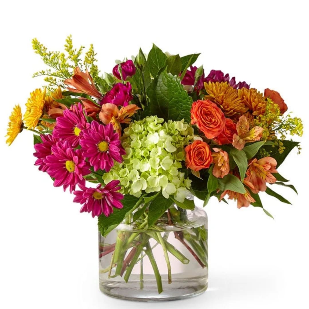 Mixed bouquet of pink, orange, and yellow flowers in a clear glass vase