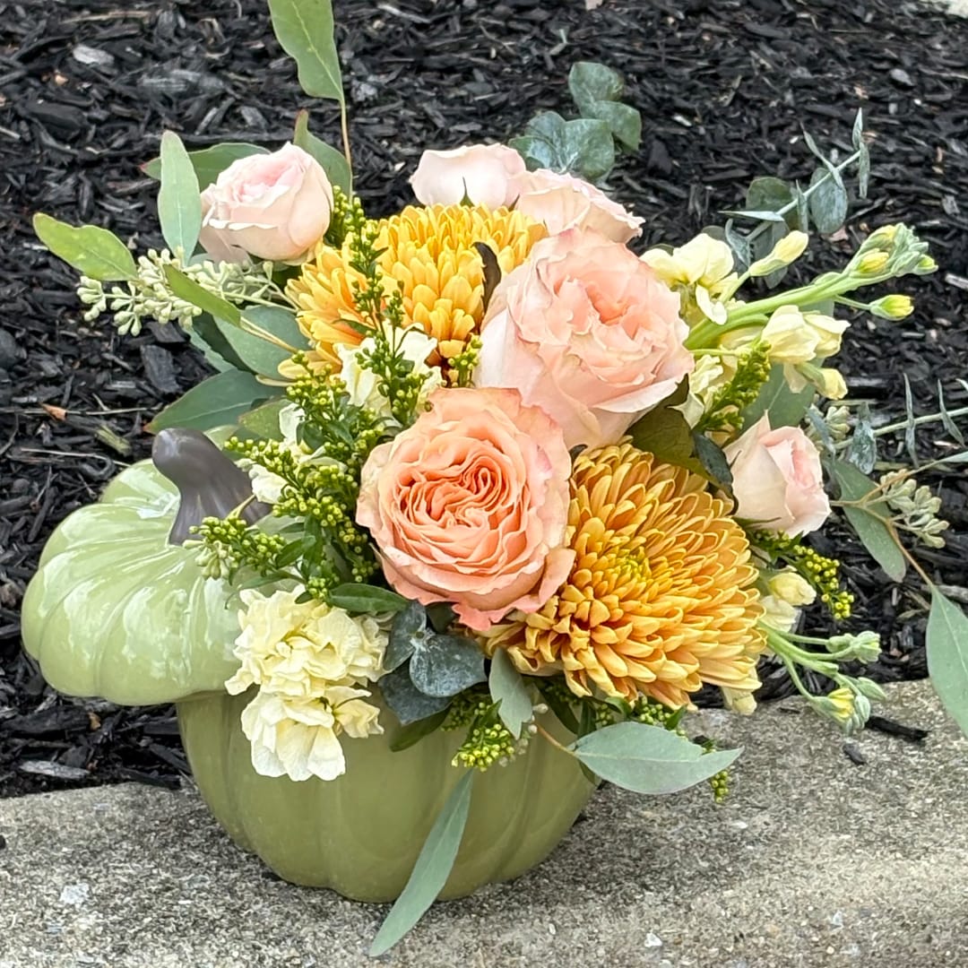 Peach roses and yellow chrysanthemums in a green pumpkin vase
