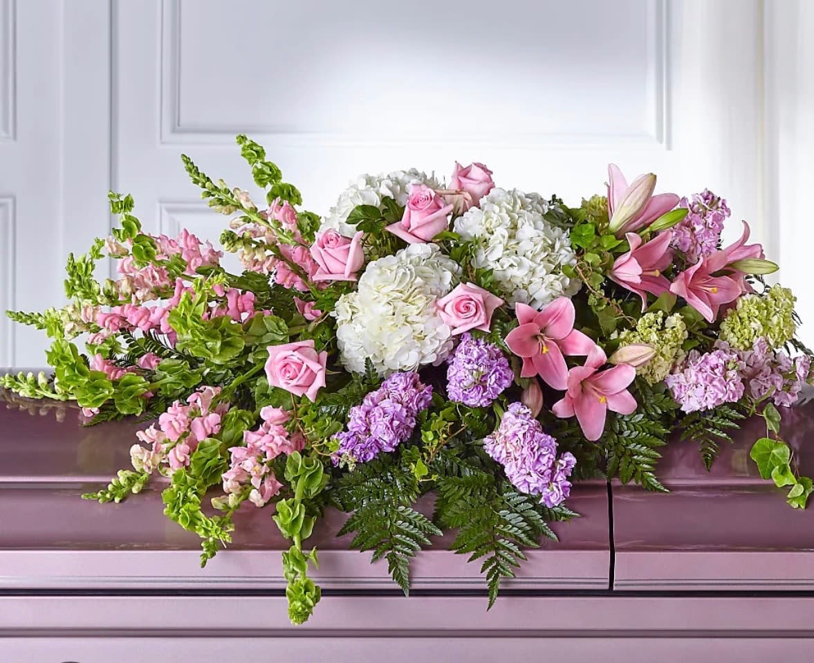 Pink and white floral casket spray with lilies, roses, and hydrangeas
