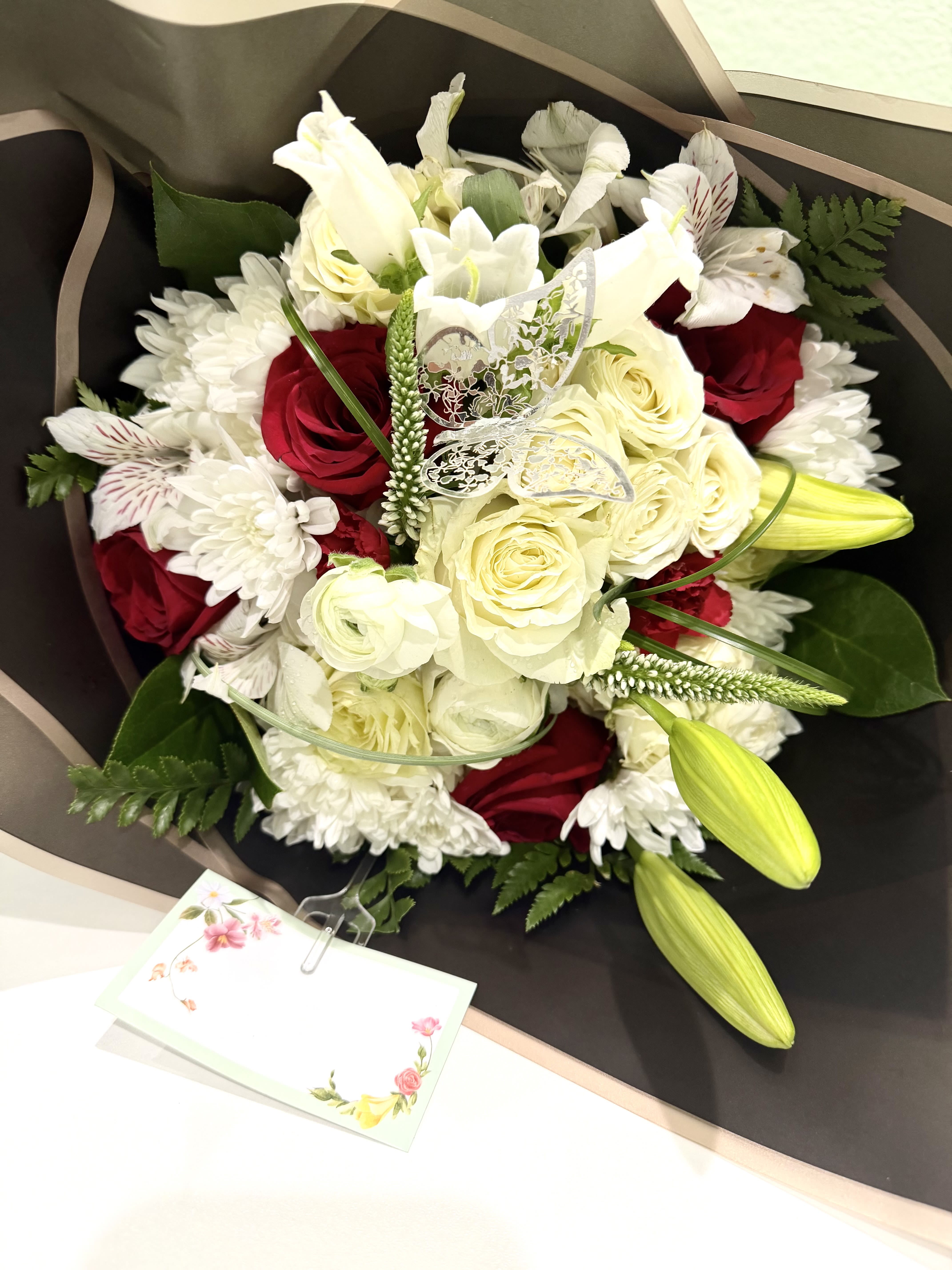 Sweet Hello - Sweet Hello is a light, cheerful bouquet designed for everyday moments. Soft red and white roses paired with fresh seasonal flowers create a warm, friendly feel—perfect for saying hello, sharing a smile, or brightening someone’s day on the go. Simple, fresh, and full of charm, it turns ordinary greetings into something special.This bouquet does not come in a vase.