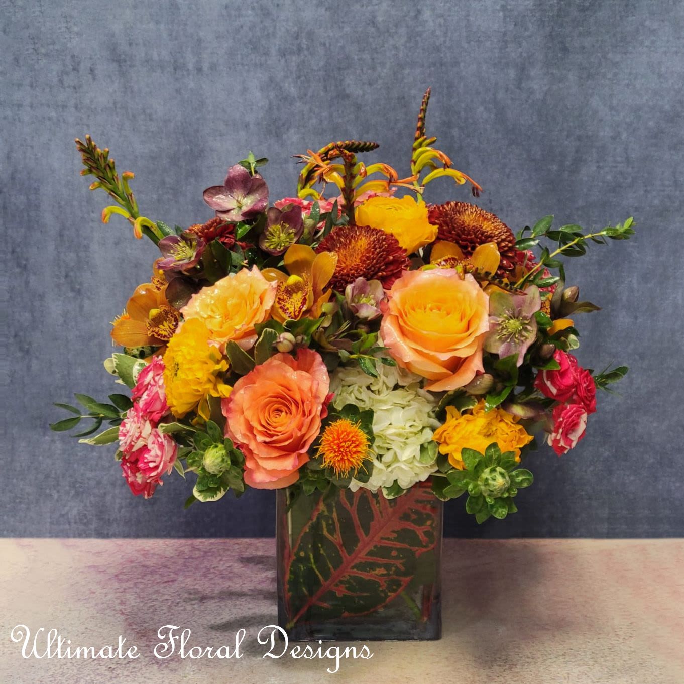 Colorful bouquet of roses, orchids, and chrysanthemums in a square vase