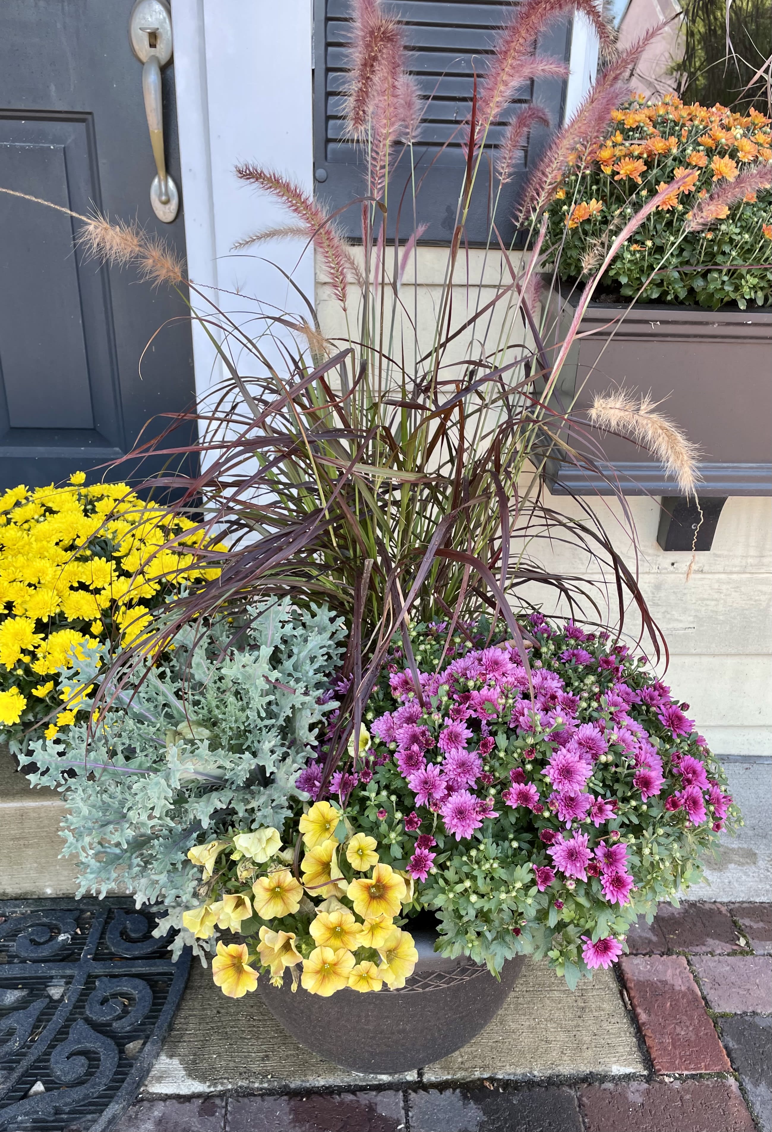 Mixed potted flowers with pink and yellow blooms and tall ornamental grass