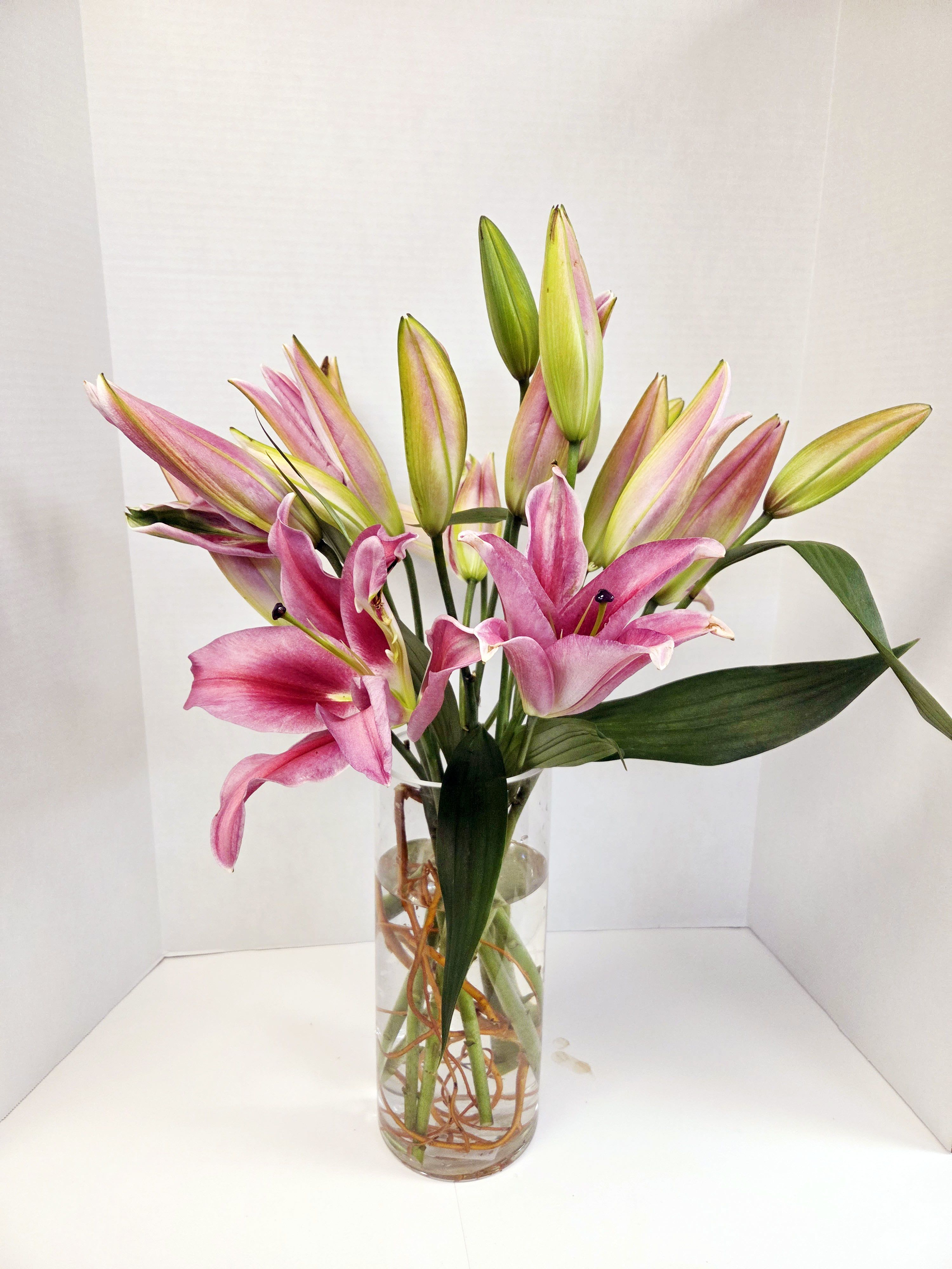 Pink and green lilies arranged in a clear glass vase