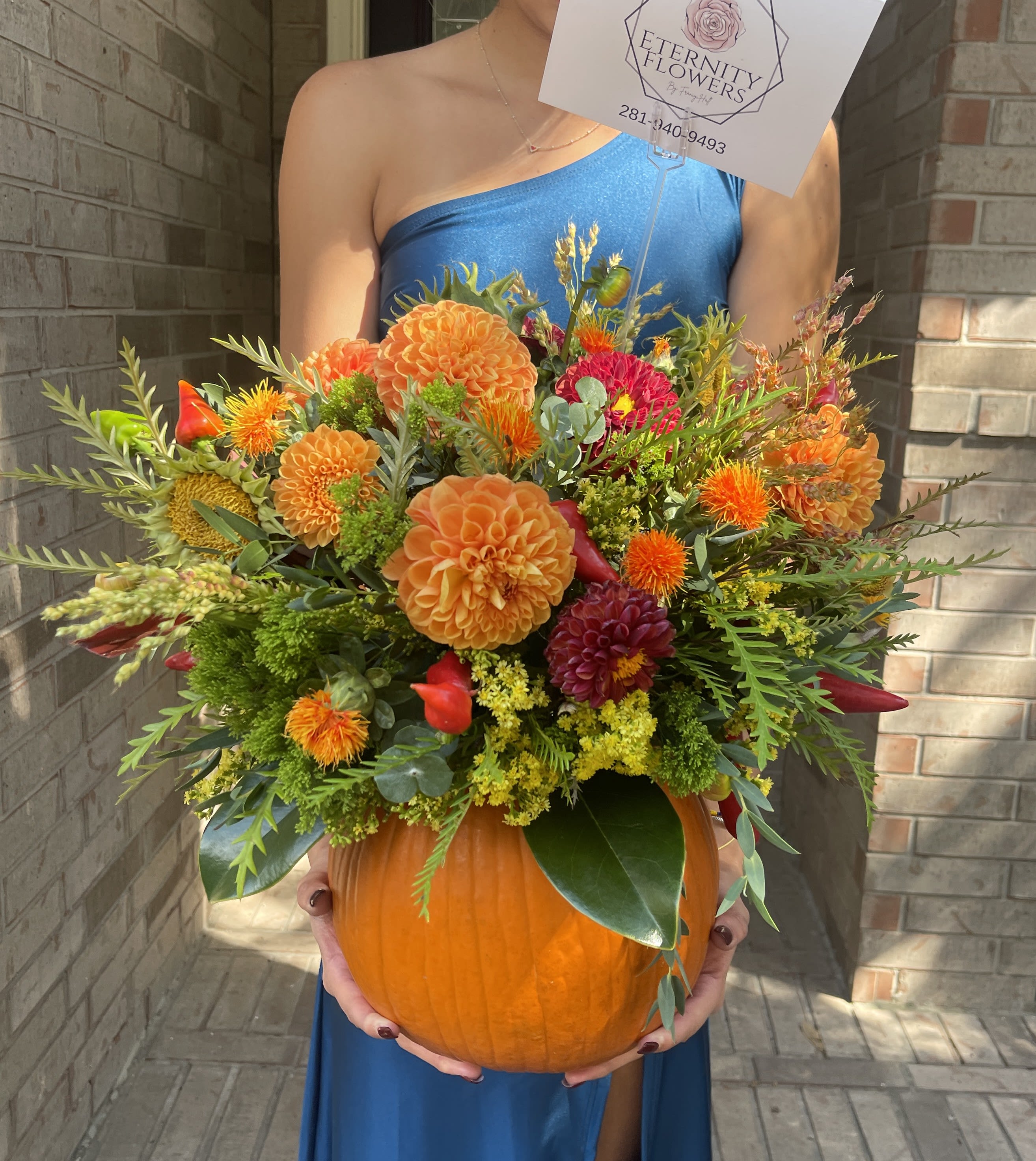 Orange and red floral arrangement in a pumpkin container