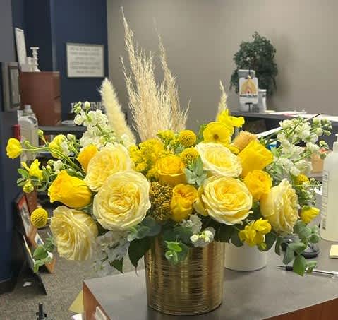 Yellow and white floral arrangement in a gold vase