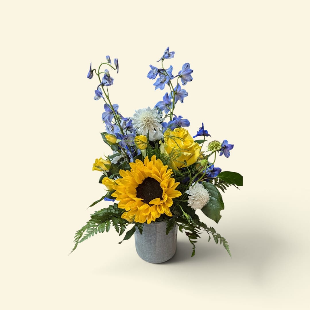 Sunflower and blue flower arrangement in a gray vase