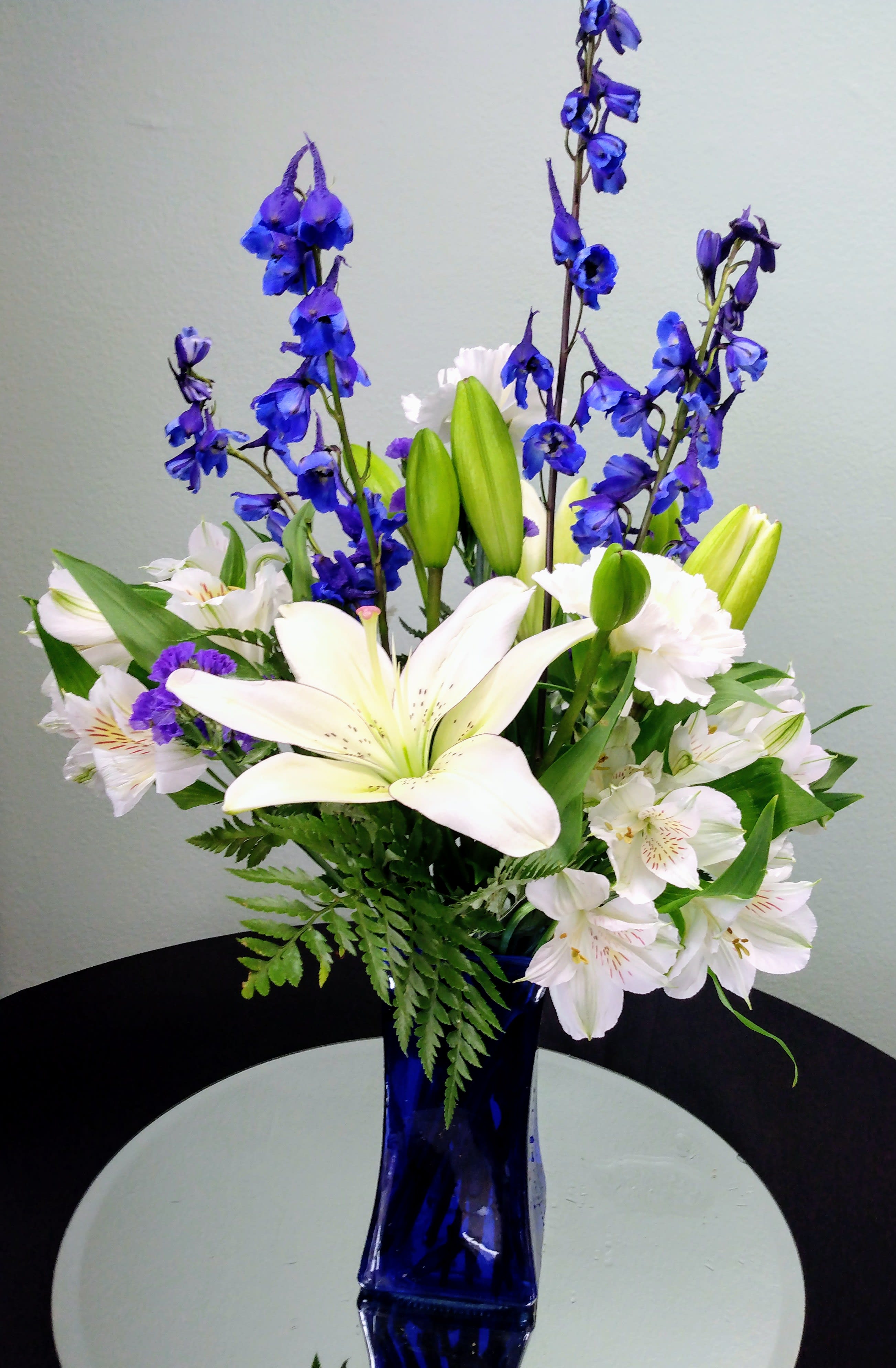 Blue and white flower arrangement in a tall cobalt vase