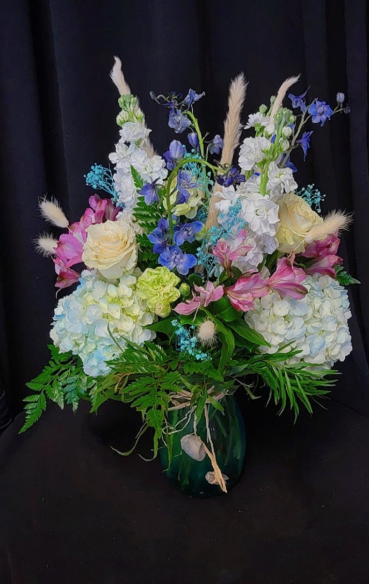 Mixed bouquet of pastel flowers in a dark vase