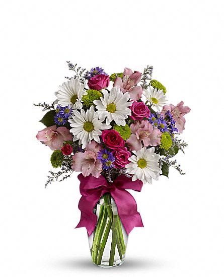 Bouquet of white daisies, pink roses, and pink lilies in a glass vase with a ribbon