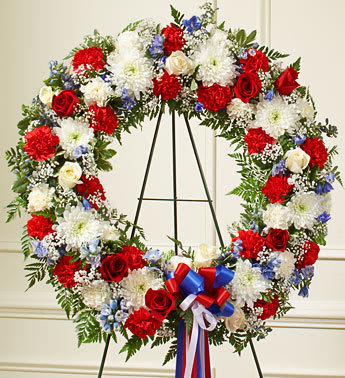 Large floral wreath with red, white, and blue flowers on a stand