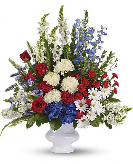 Red roses, white flowers, and blue blooms in a white vase