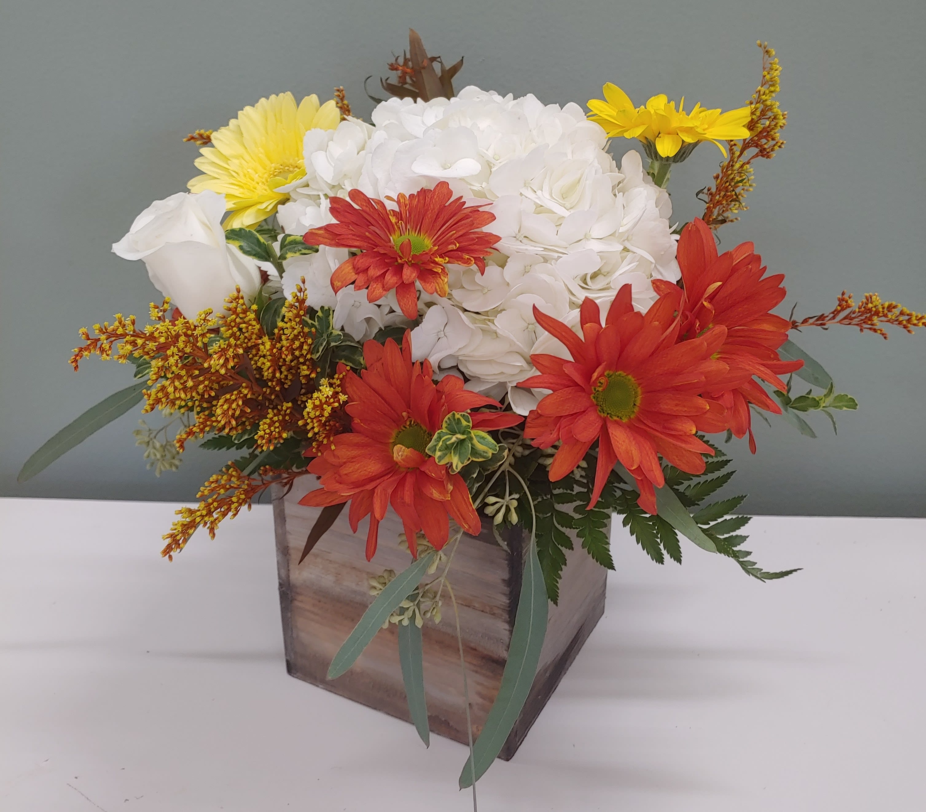 Mixed bouquet in a wooden box with white, red, and yellow flowers