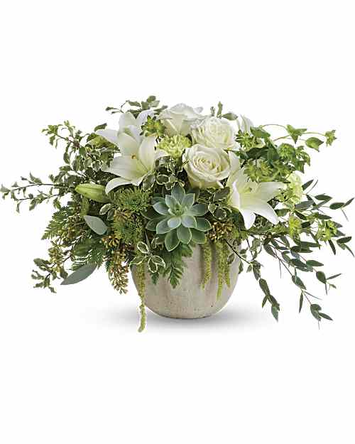 White roses and lilies in a beige vase with trailing greenery