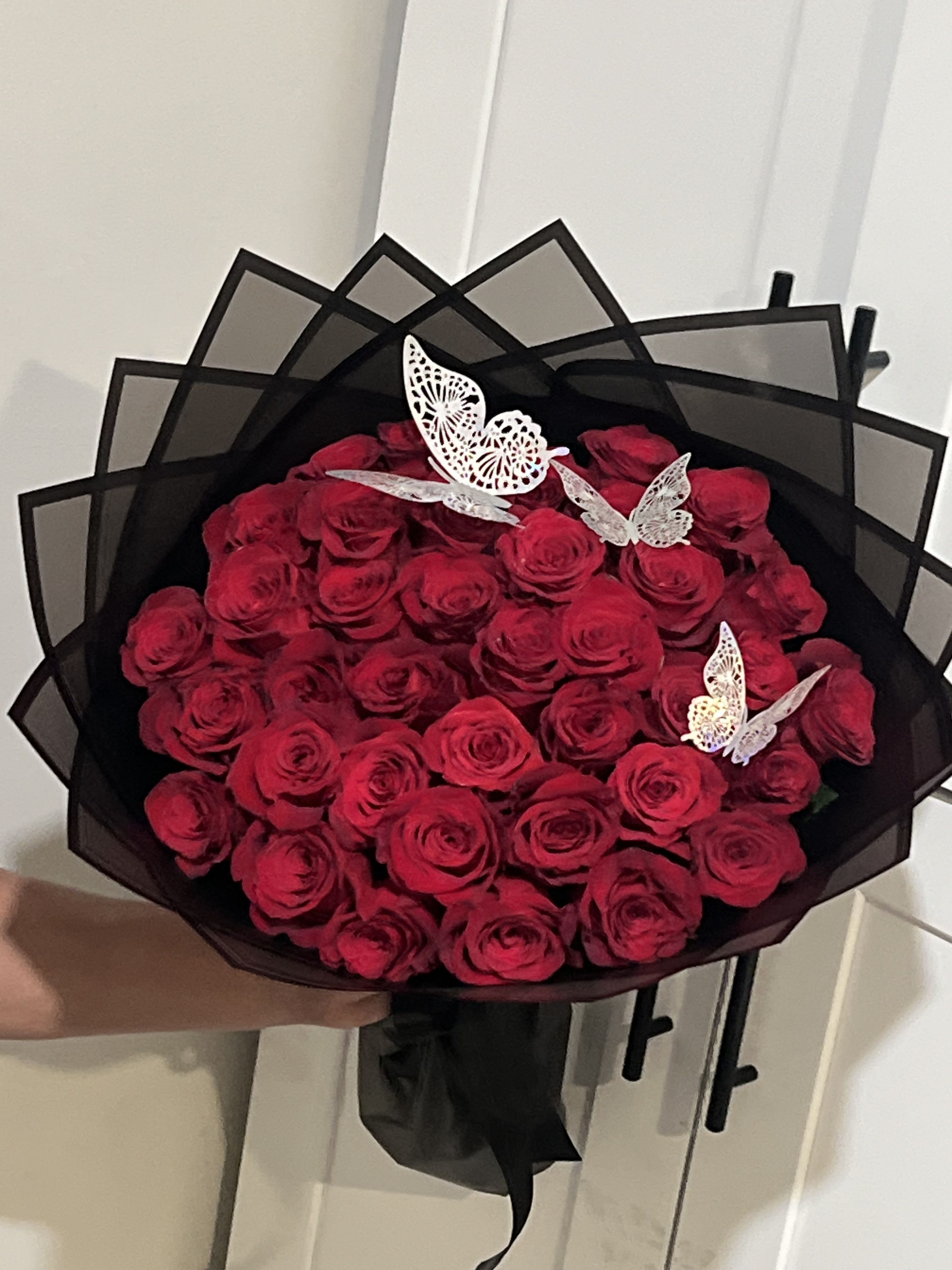 Bouquet of red roses wrapped in black paper with butterfly accents
