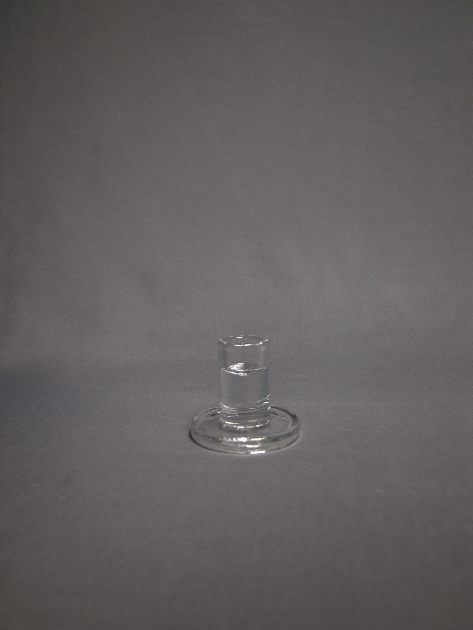Small clear glass holder with round base on gray background