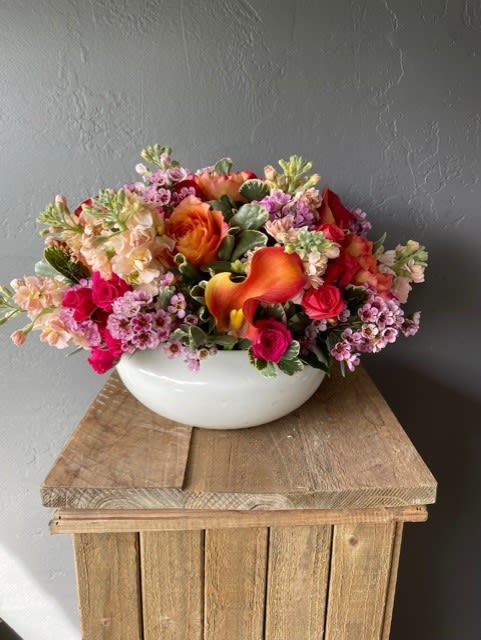 Country Living  - A generous sized white ceramic bowl filled with brightly colored flowers.