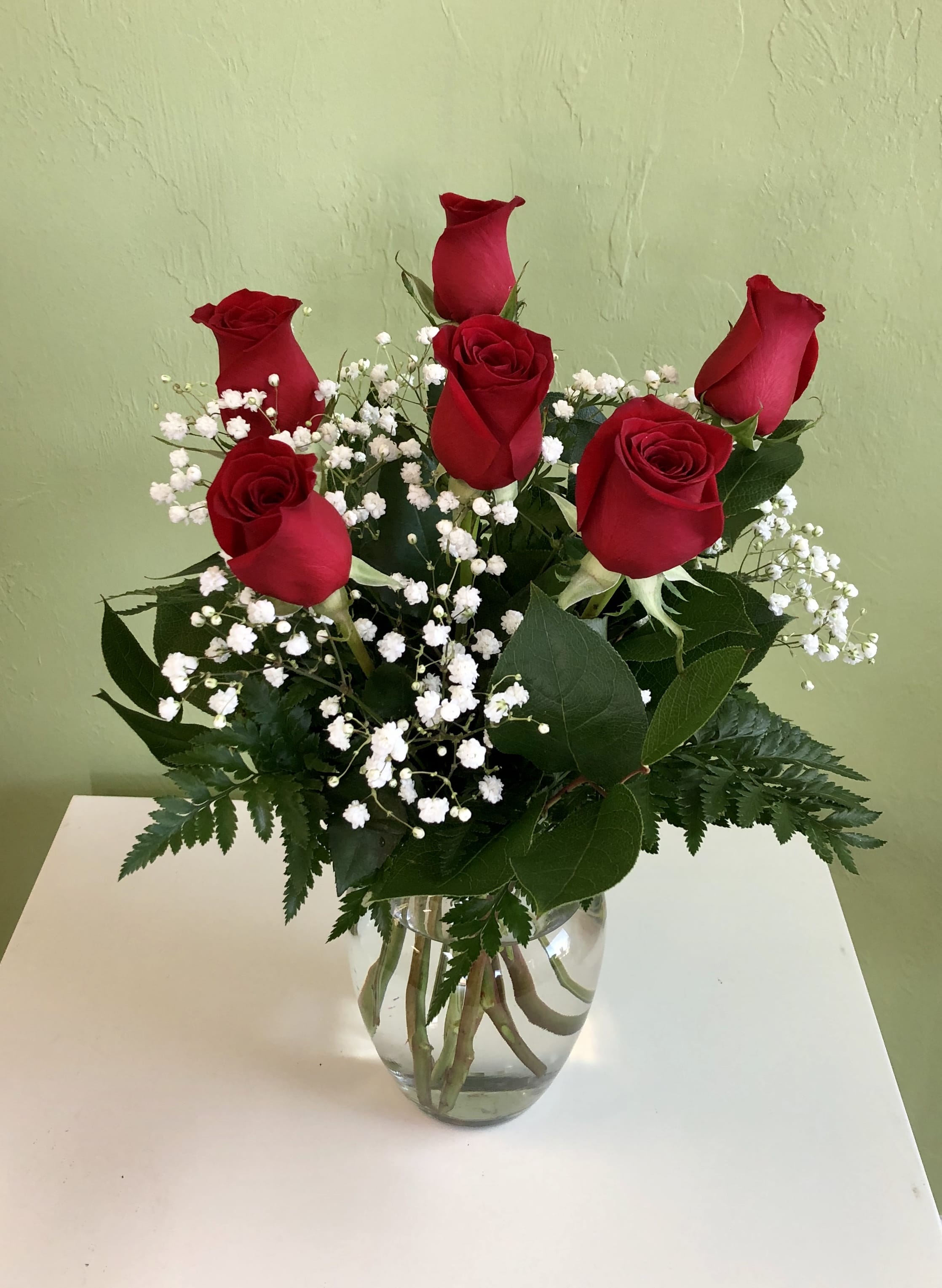 Red roses with white baby's breath in a clear glass vase