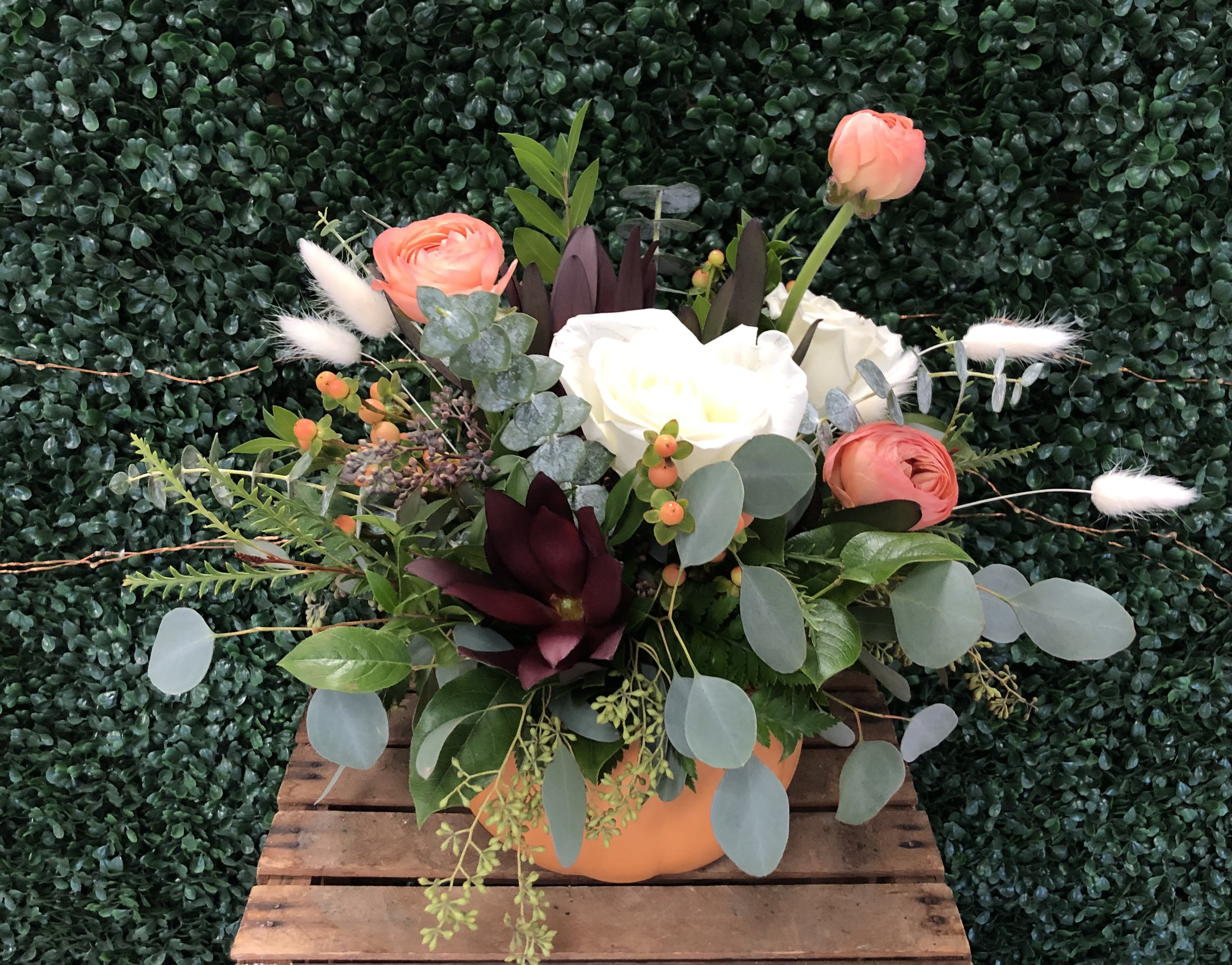 Mixed floral arrangement in an orange container with coral and white blooms