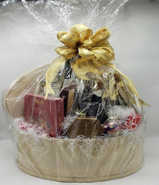 Gift basket with bottles and boxed treats wrapped in clear cellophane and a gold bow