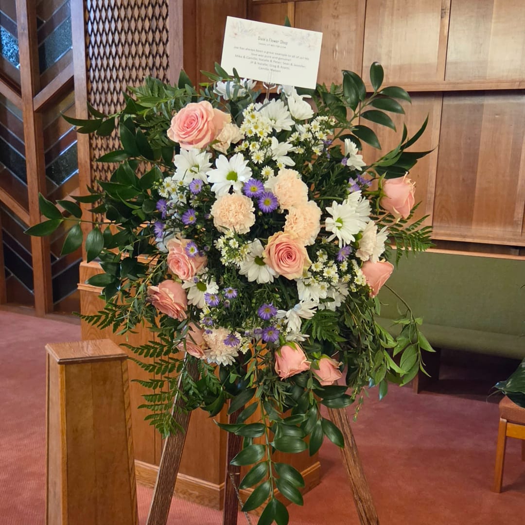 Standing floral spray with pink roses, white daisies, and purple accents